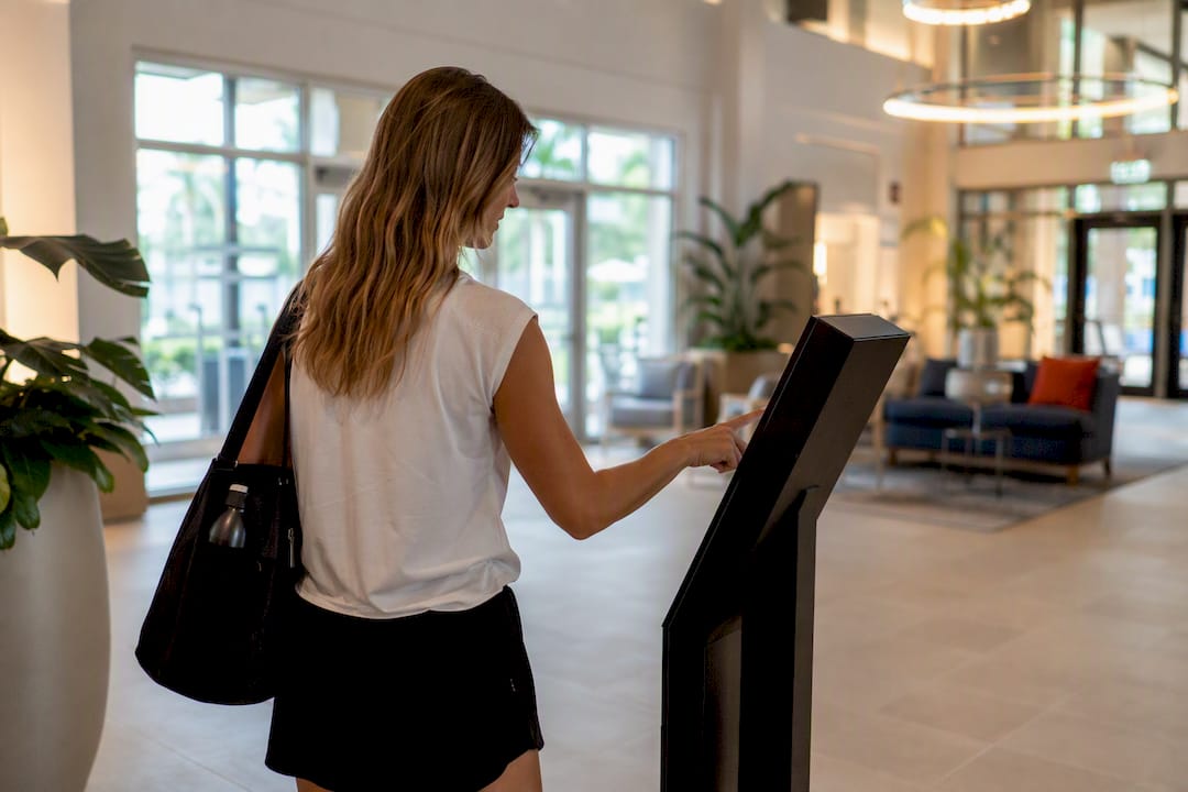 Hands using touch kiosk in hotel lobby