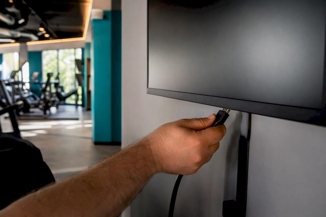 Close-up hands plugging cable into digital signage screen
