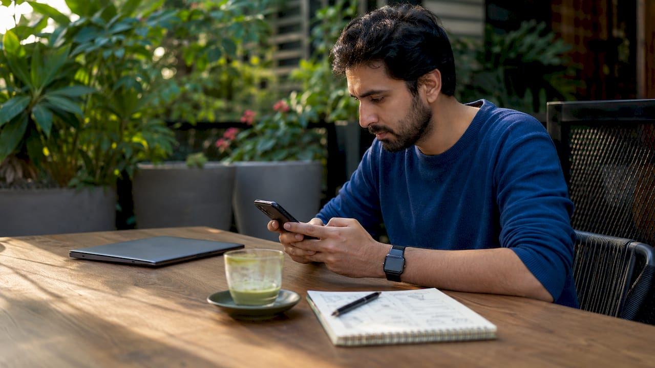 Man checking bank statements on phone at café