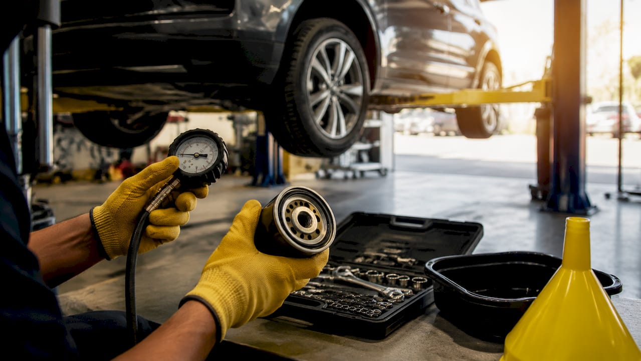 Mechanic hands holding tire gauge and oil filter