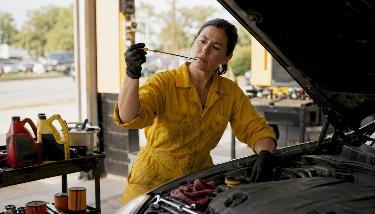 Technician checking engine oil in service bay