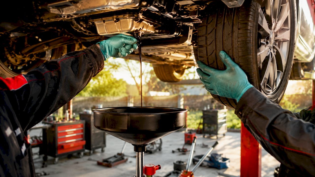 Hands performing tire rotation and oil change simultaneously