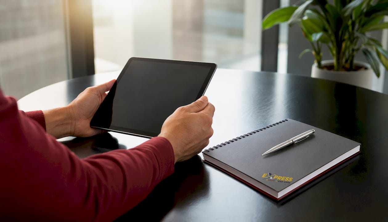 Hands holding tablet over wooden table with coffee