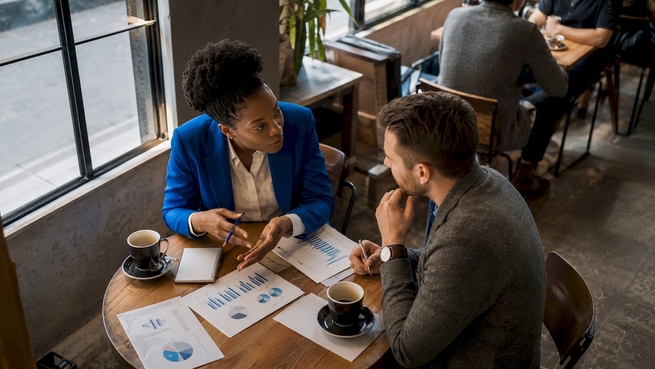Two investors discussing strategy at co-working table
