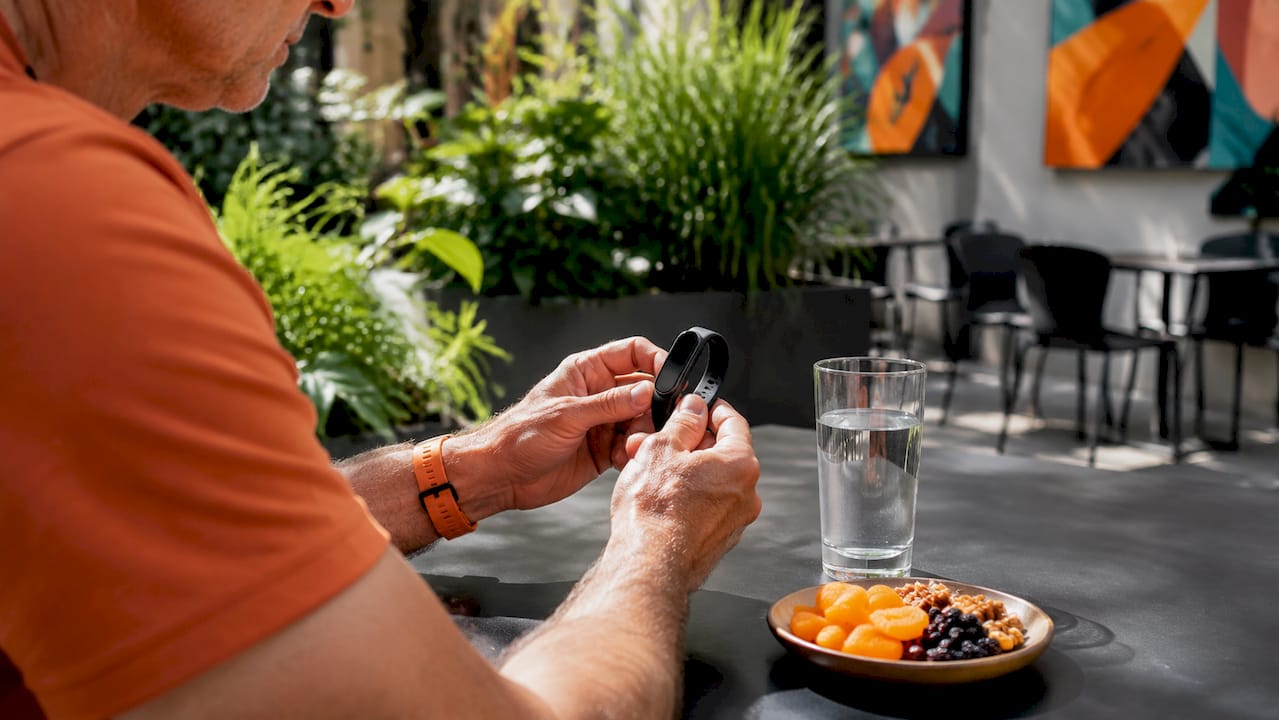 Hands holding fitness tracker with fasting items