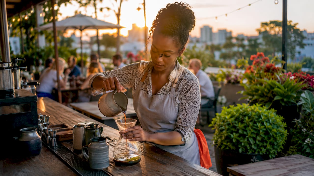 Hands pouring cold brew coffee in café