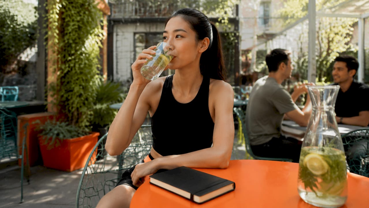 Woman drinking water at kitchen table during fast