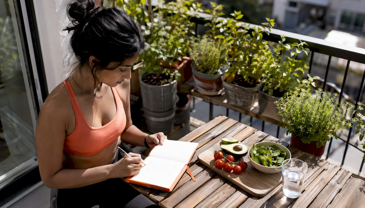 Woman planning time-restricted eating schedule at kitchen table.