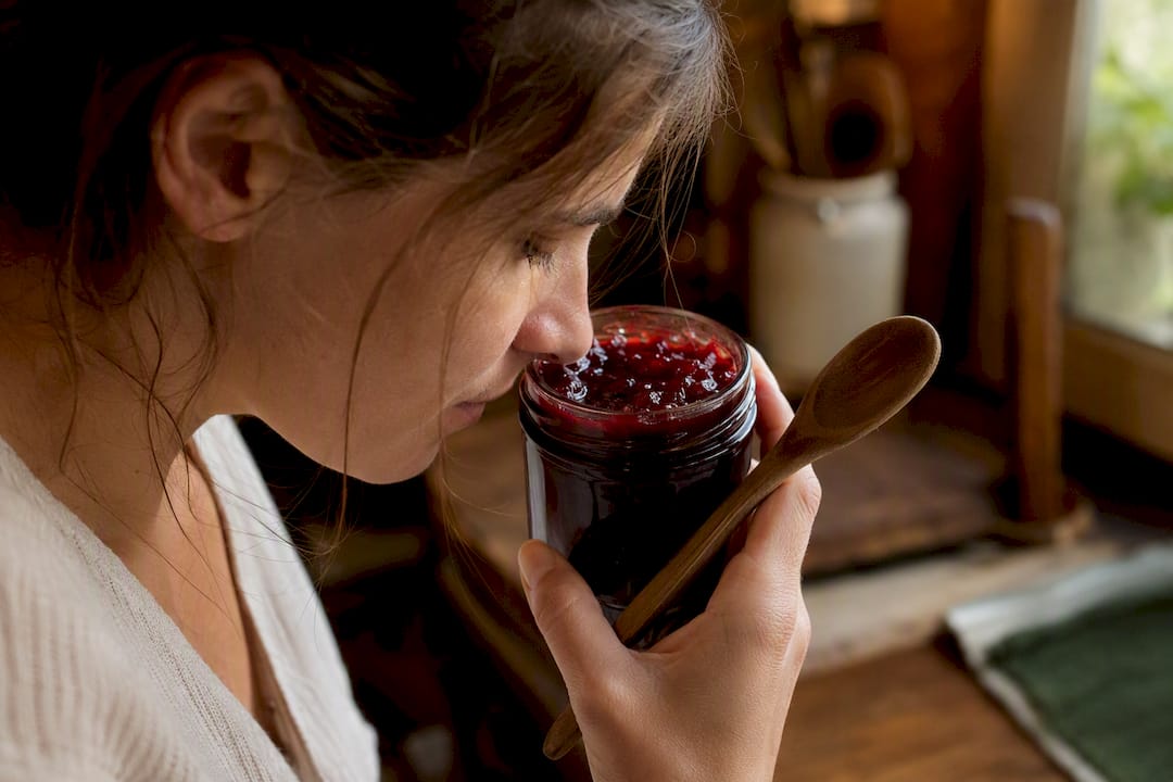 Person riecht an offener Fruchtmarmelade im Glas