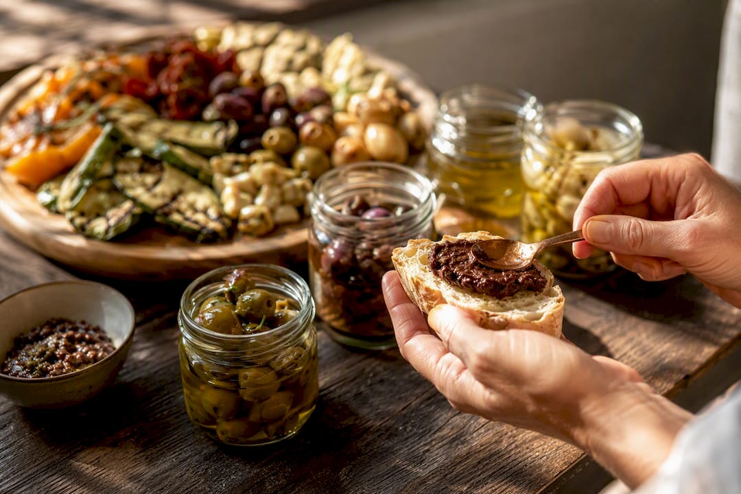 Nahaufnahme einer Hand, die handgemachte Antipasti auf Crostini serviert