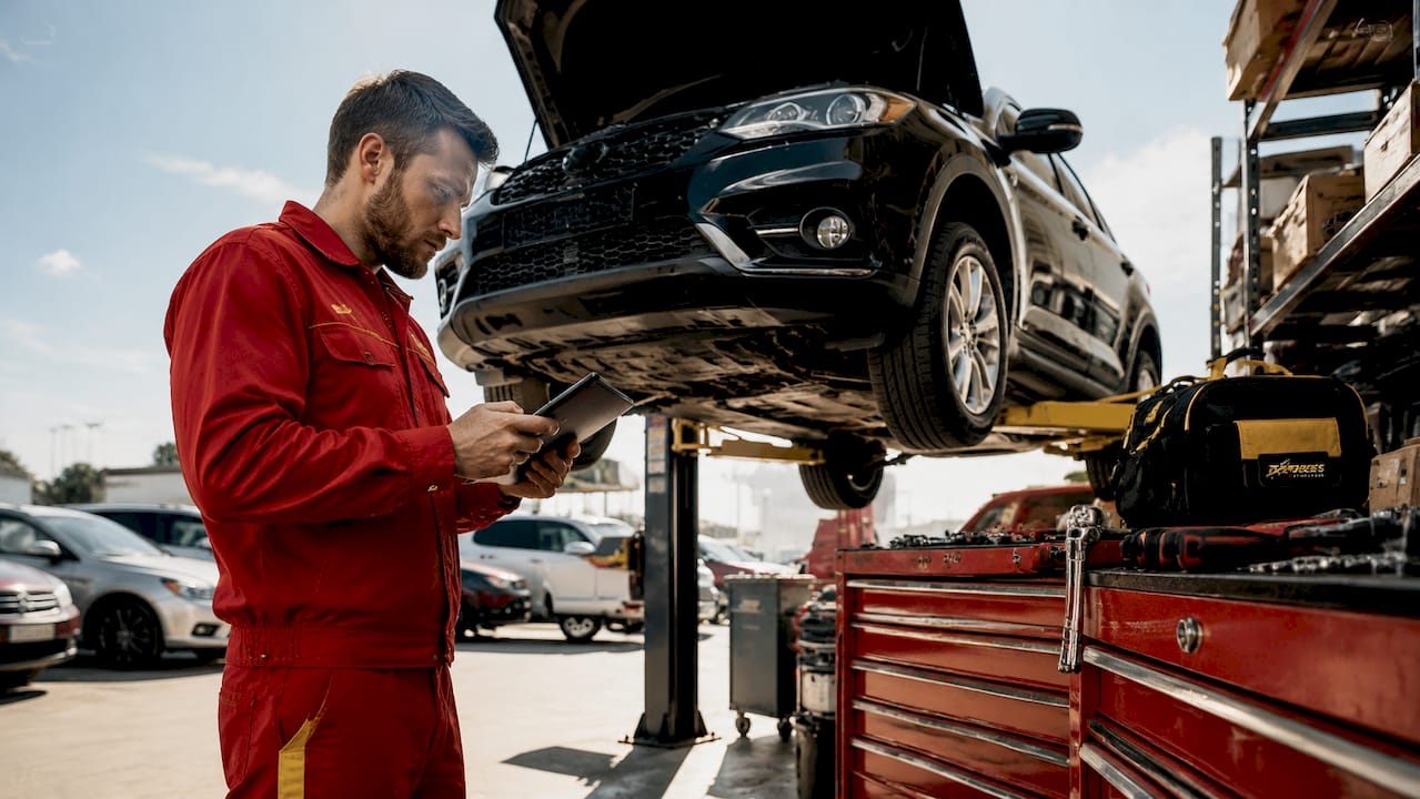Dealership technician using diagnostic tablet on SUV