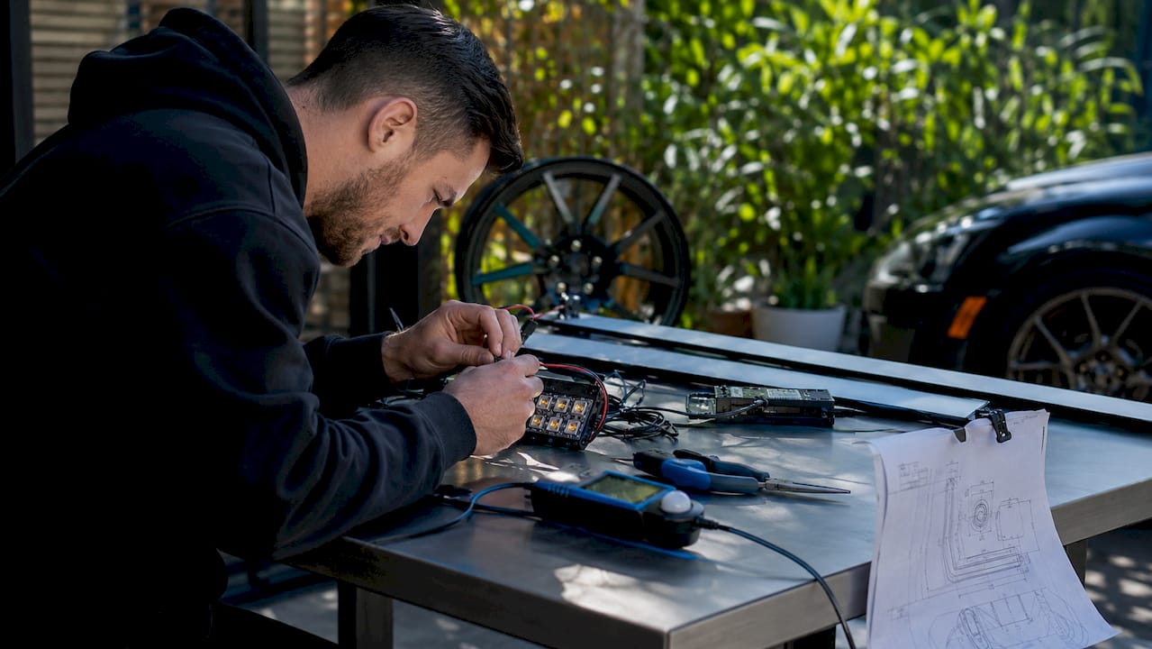 Hands assembling car lighting components on workbench