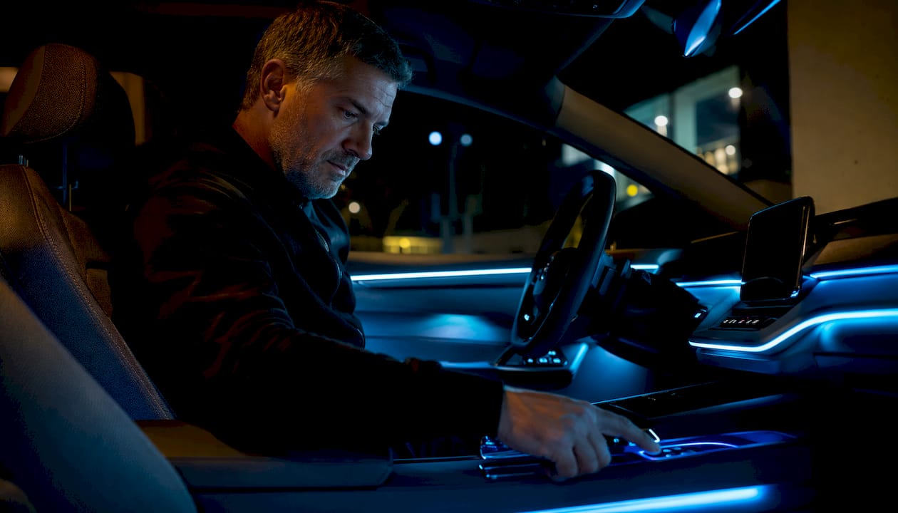 Car driver adjusting ambient interior lighting