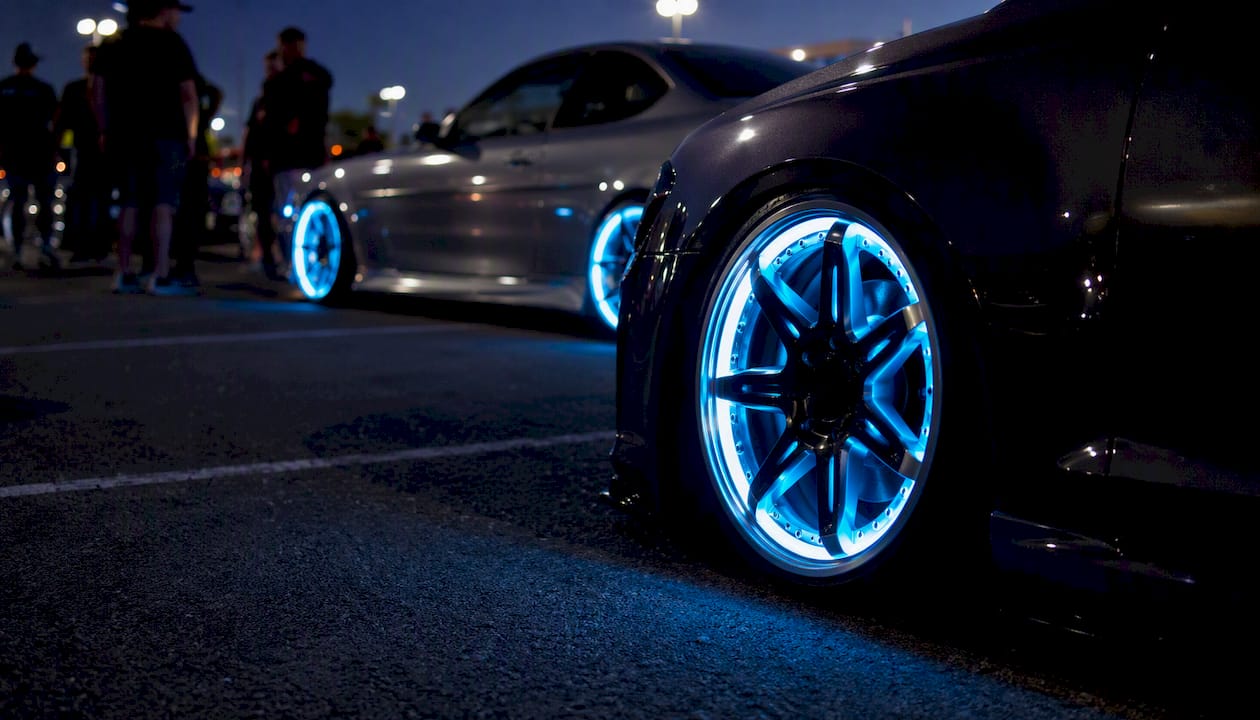Lit wheel rims glowing at a nighttime car show