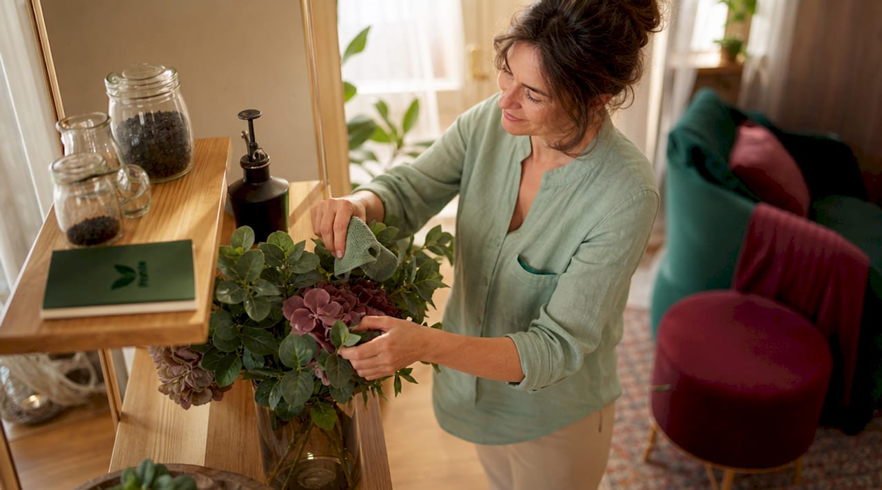 Une femme dépoussière soigneusement des fleurs artificielles avant de les ranger.