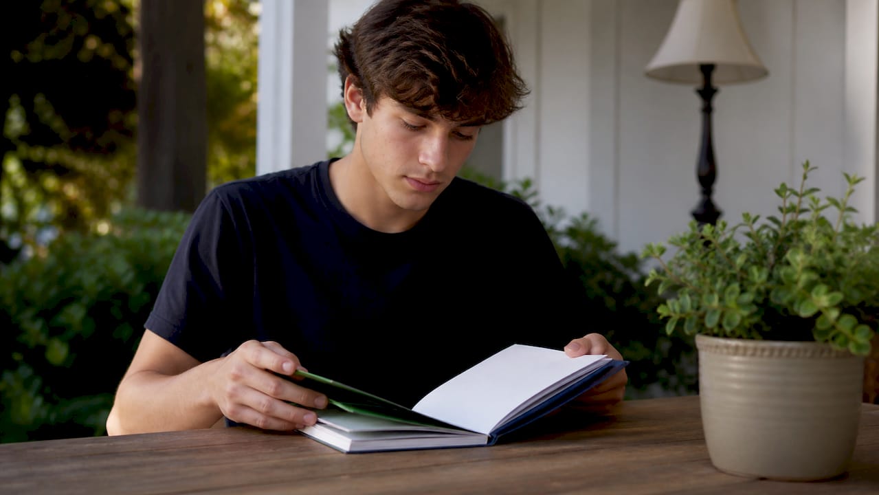 Student hands near planner and laptop on desk