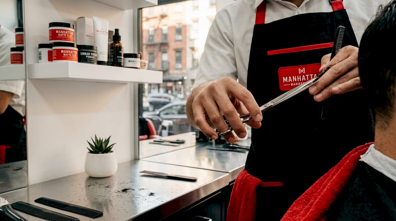 Barber hands using long scissors for haircut
