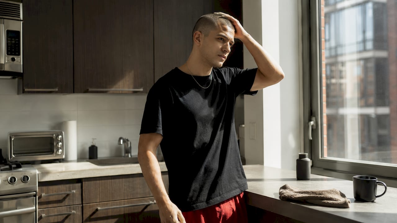 Man styling buzz cut in bathroom mirror