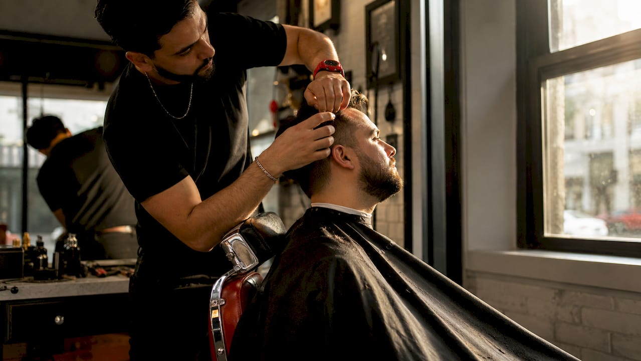 Barber examining client’s hair density on scalp