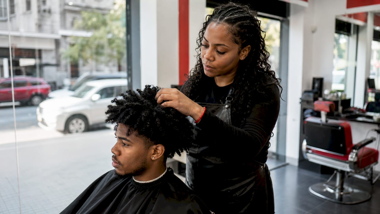 Barber examining client’s curly hair texture