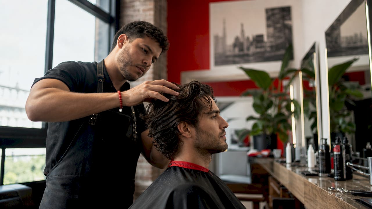 Barber inspecting a man's hair texture in shop