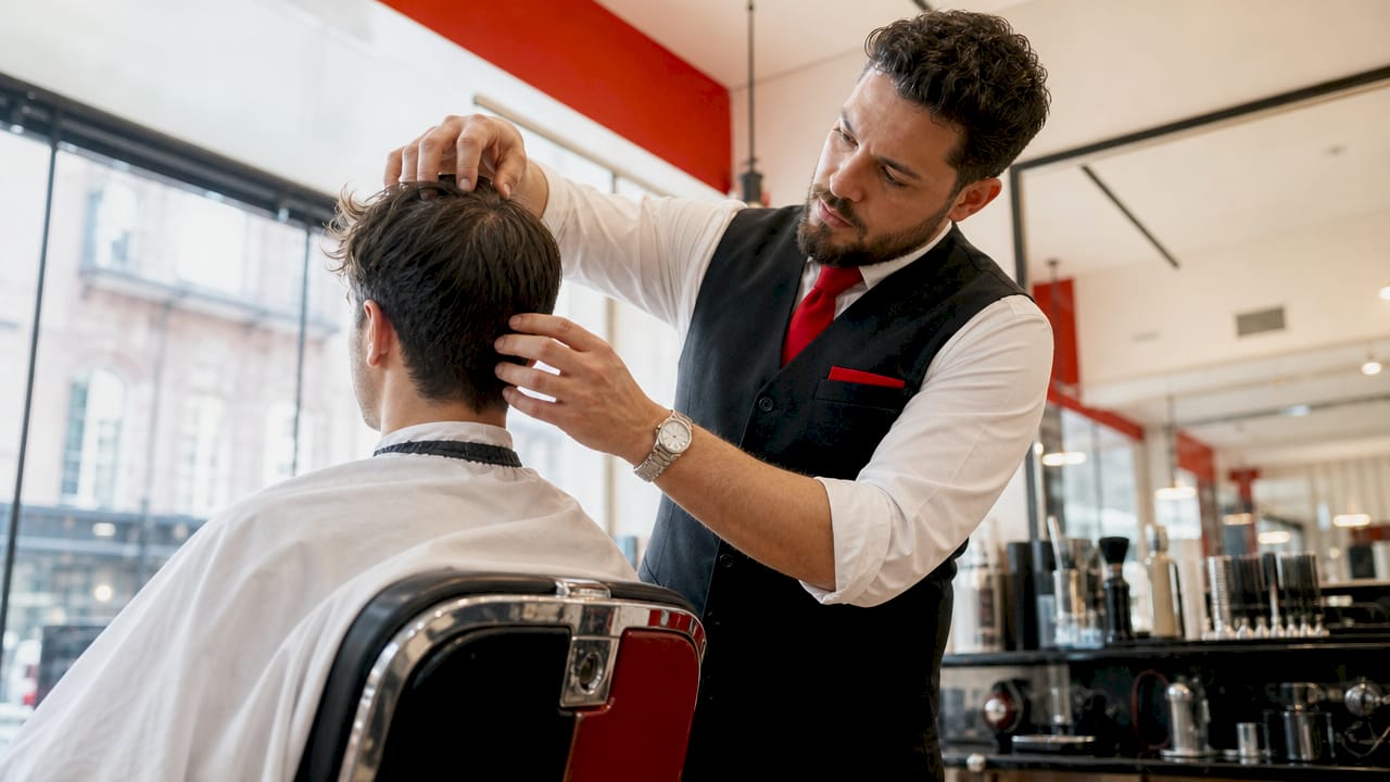 Barber examining client's hair growth pattern