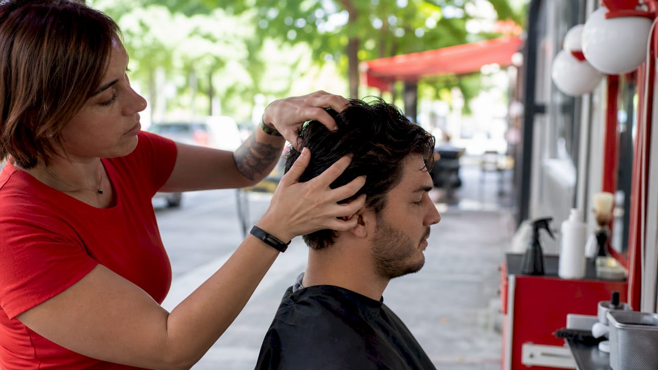 Close-up of barber's hands feeling hair growth direction