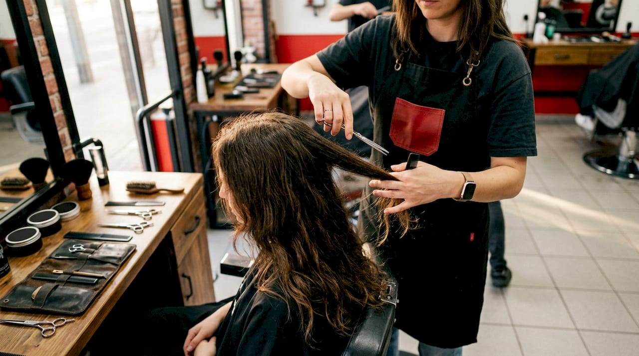 Hands performing razor cutting on textured hair ends