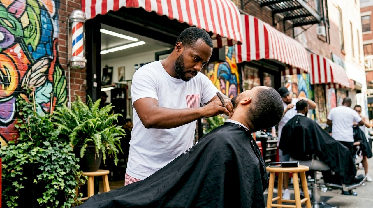 Barber performing detailed razor finishing on client neckline