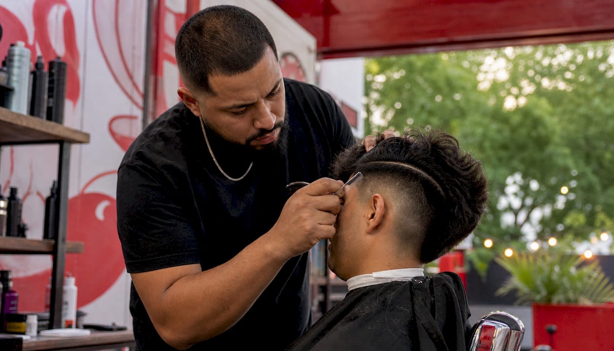 Barber shaving hard part line on male scalp