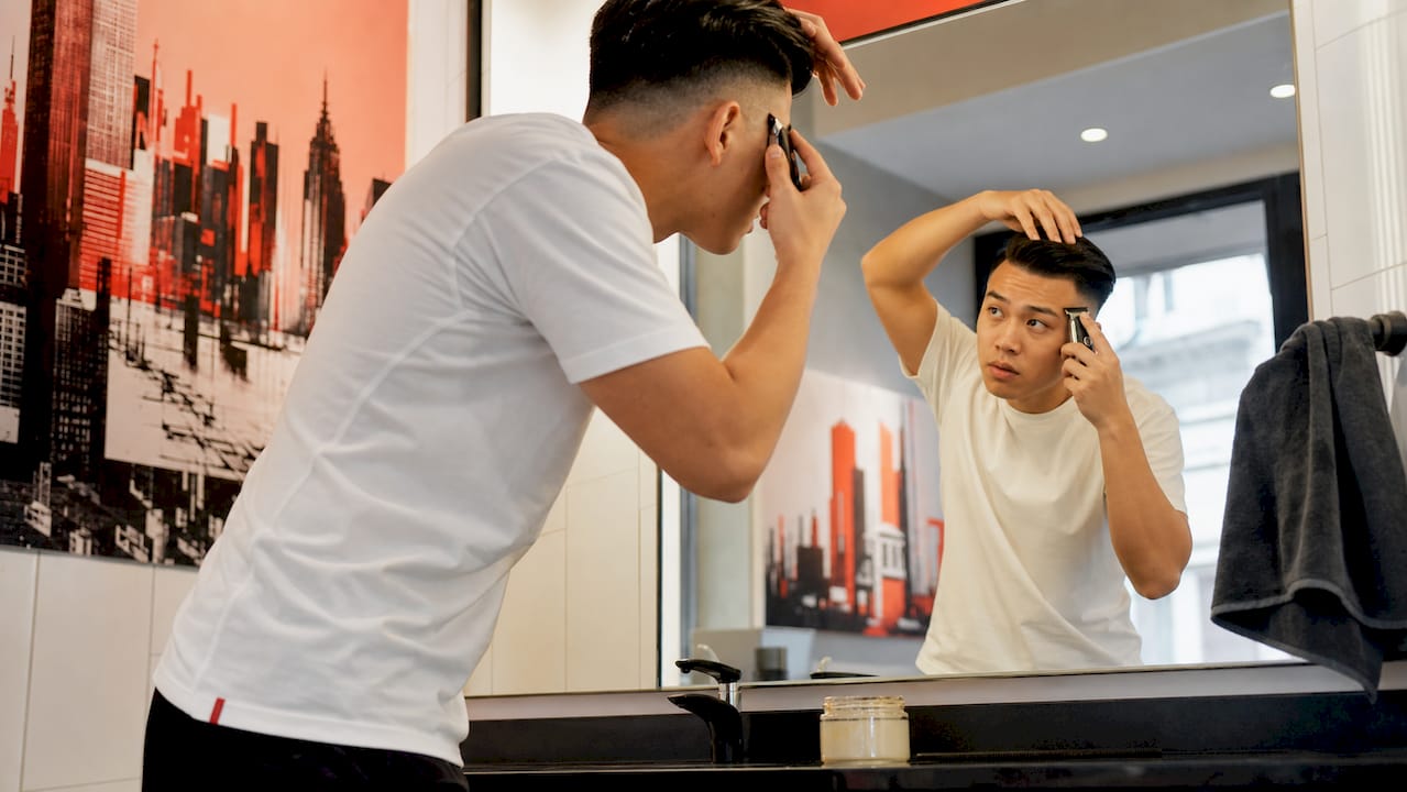 Man maintaining hard part haircut at home with trimmer