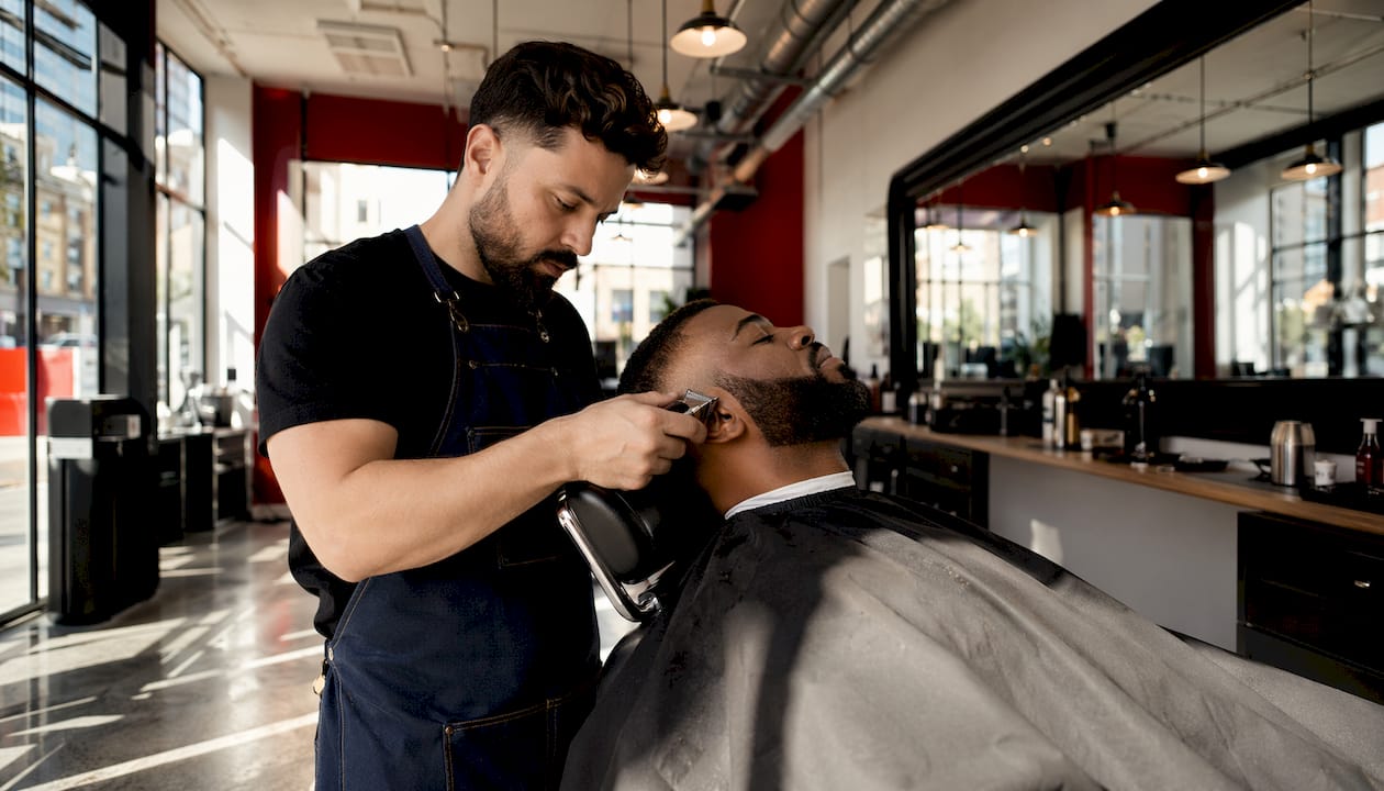 Barber carefully trimming man's beard
