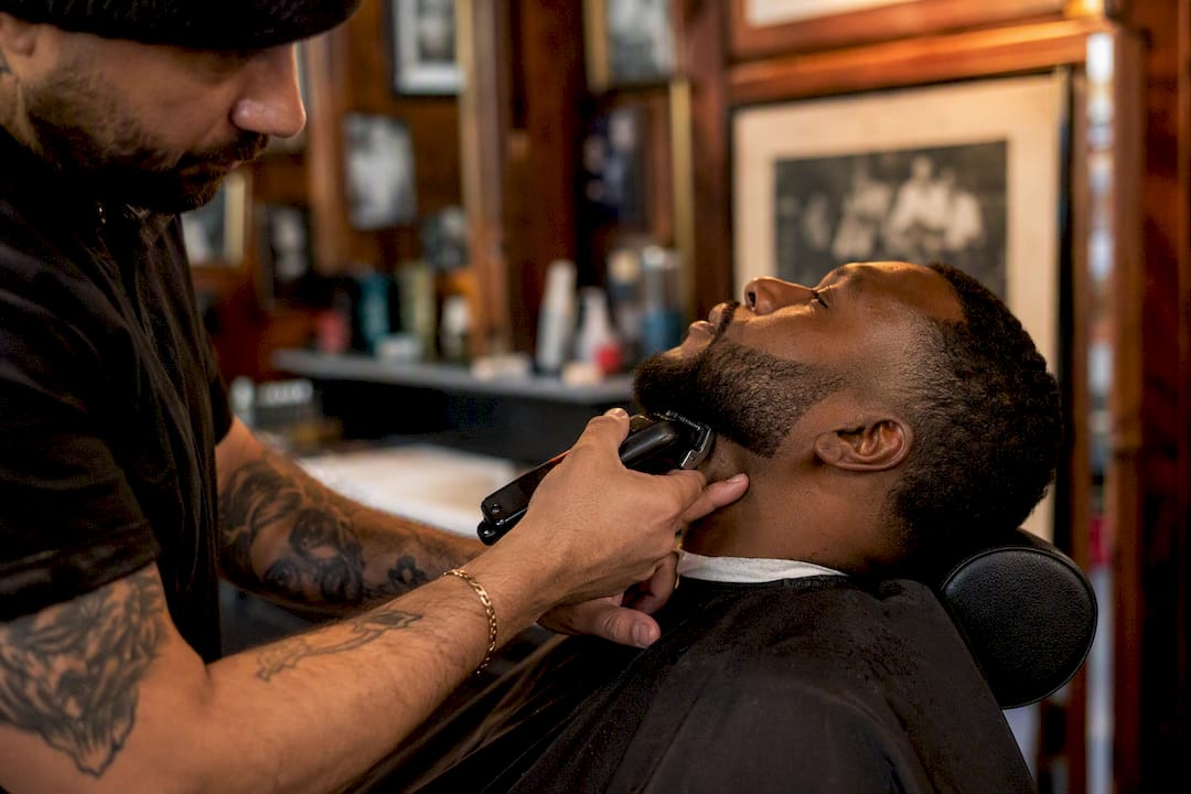 Barber fading beard with clippers side view