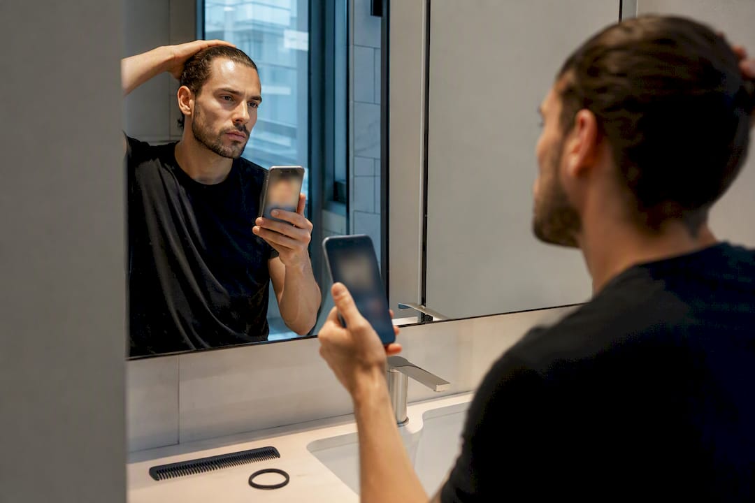 Man checking face shape with hair back