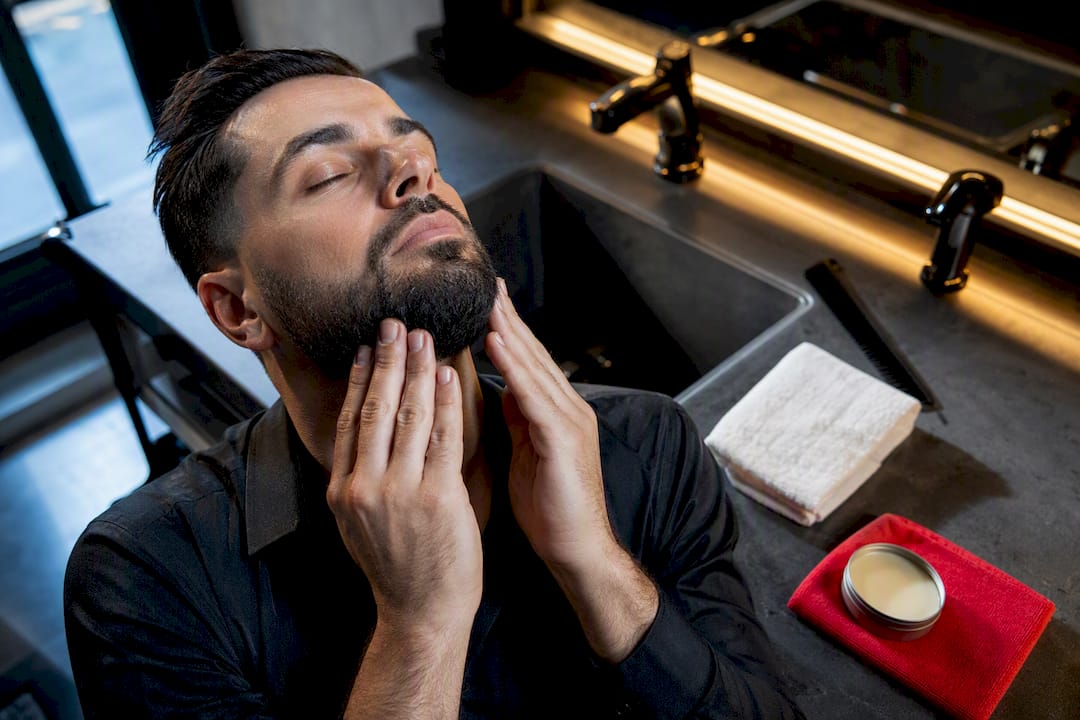 Hands applying beard oil at barbershop sink
