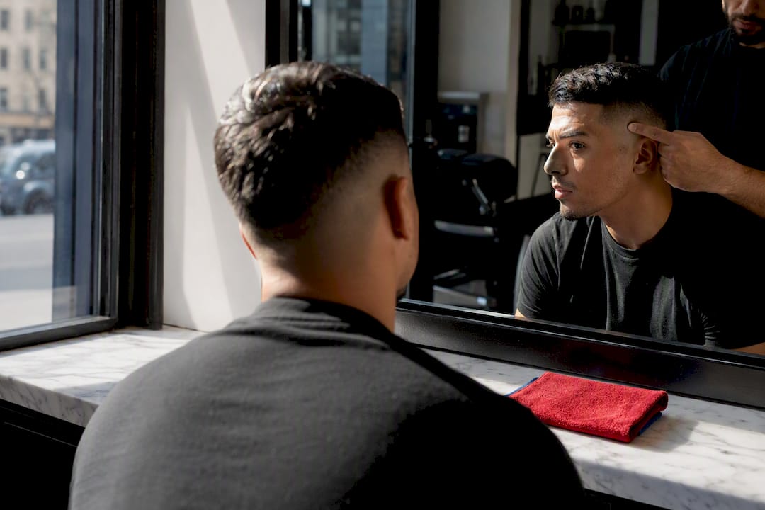 Client examining fade height in barbershop mirror