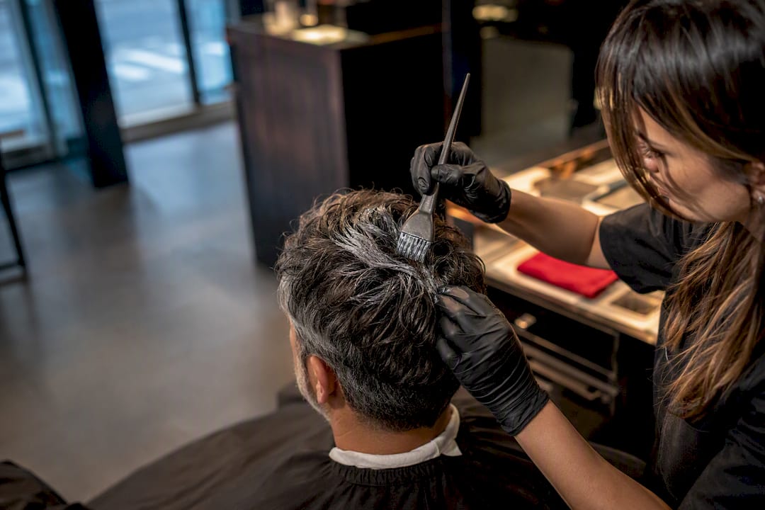 Colorist applying gray blend to salt-and-pepper hair