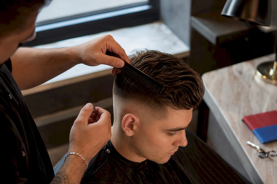 Barber checking length on top of fade