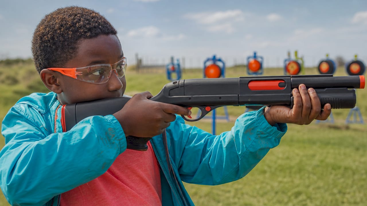 Boy practicing laser clay shooting indoors