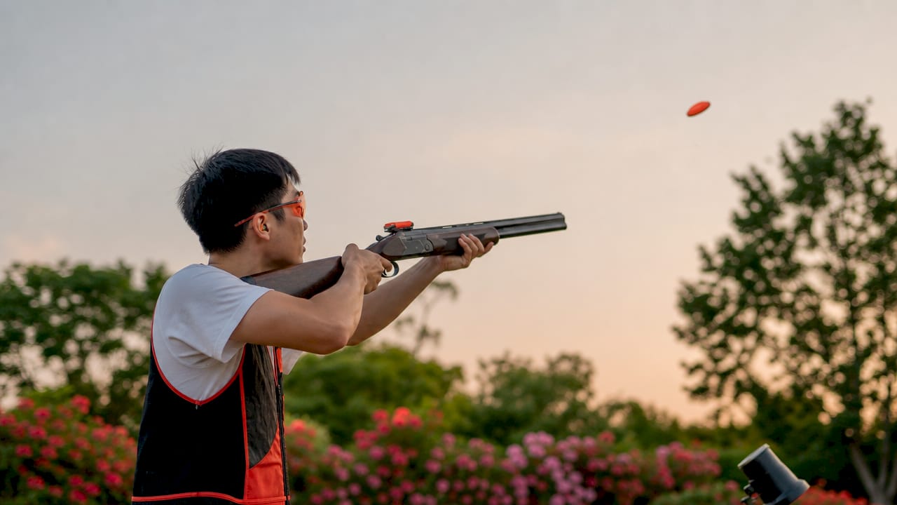 Man focusing on laser clay target indoors