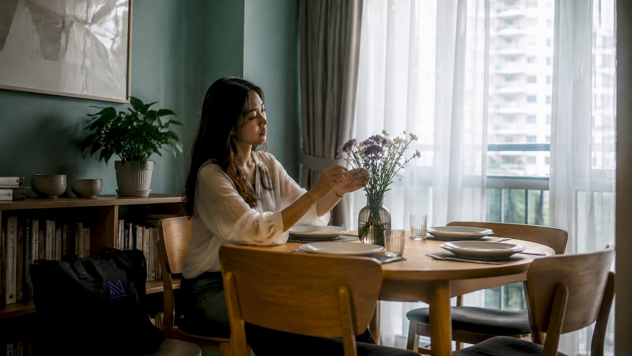 Woman arranging centerpiece on dining table in Singapore home