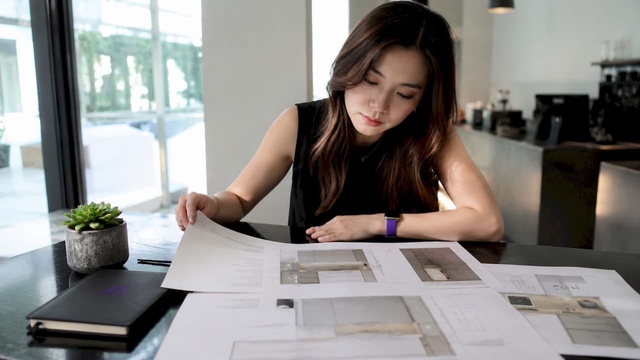 Singaporean designer reviewing kitchen cabinet blueprints