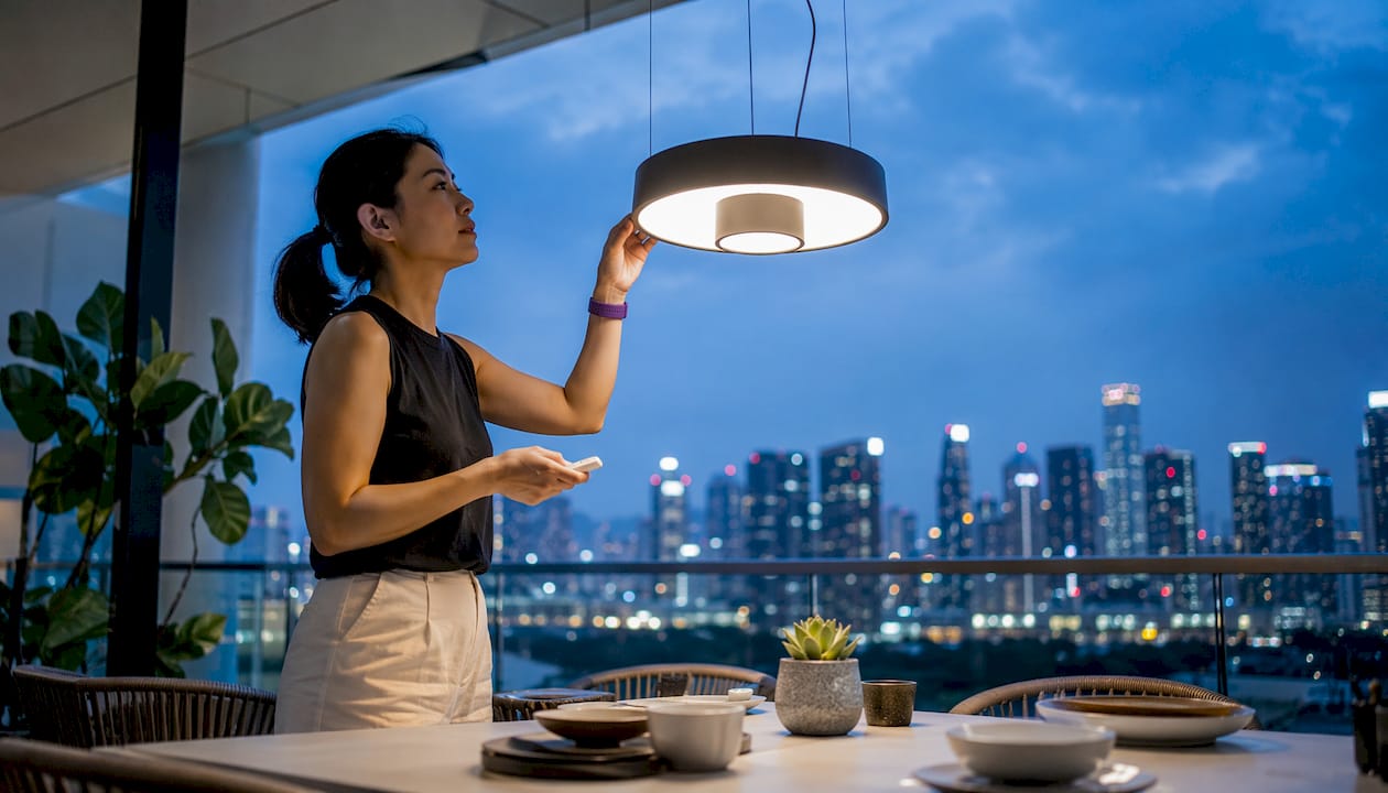 Singaporean woman adjusting pendant light in condo