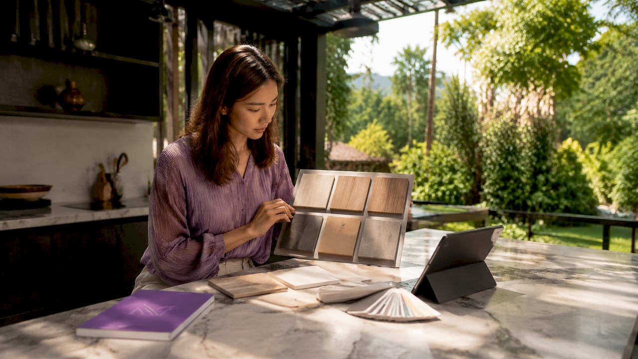 Asian woman reviewing kitchen cabinet materials in modern kitchen