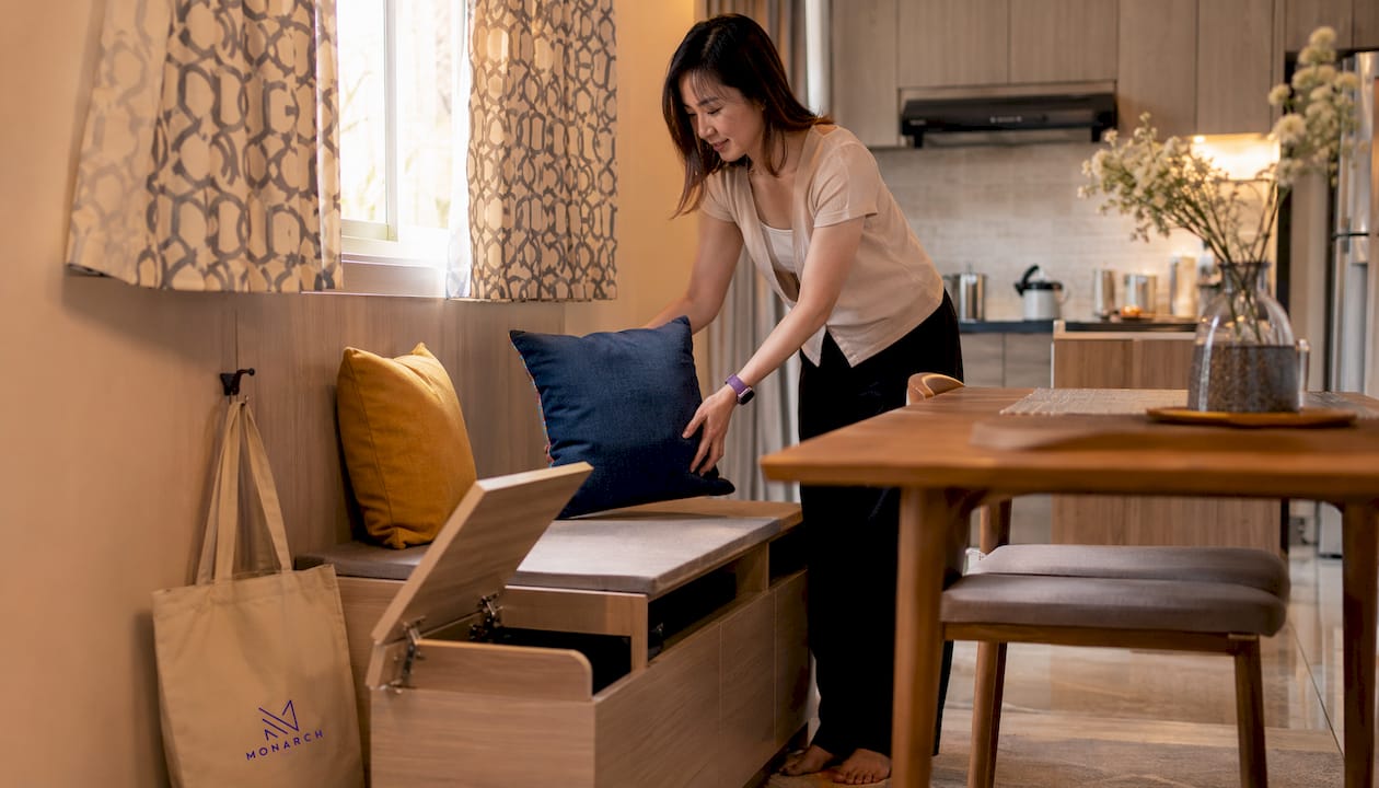 Singaporean woman arranging cushions on storage bench