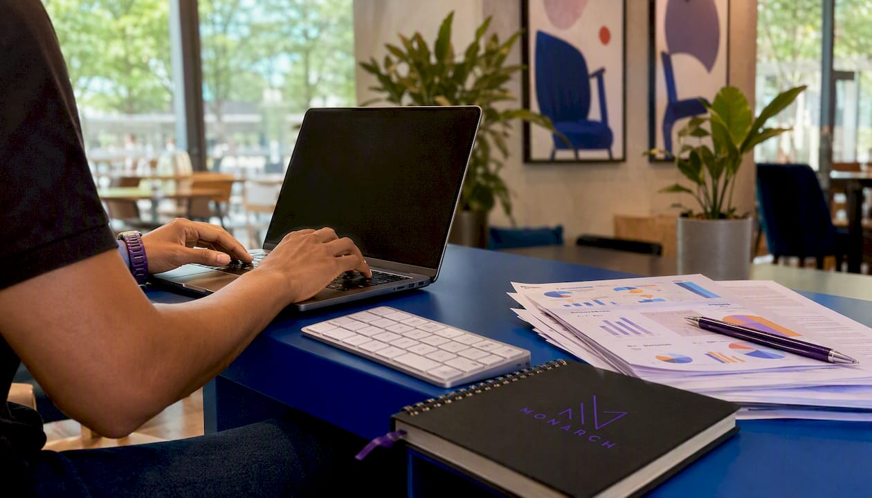 Overhead close-up of hands typing on keyboard with marketing materials