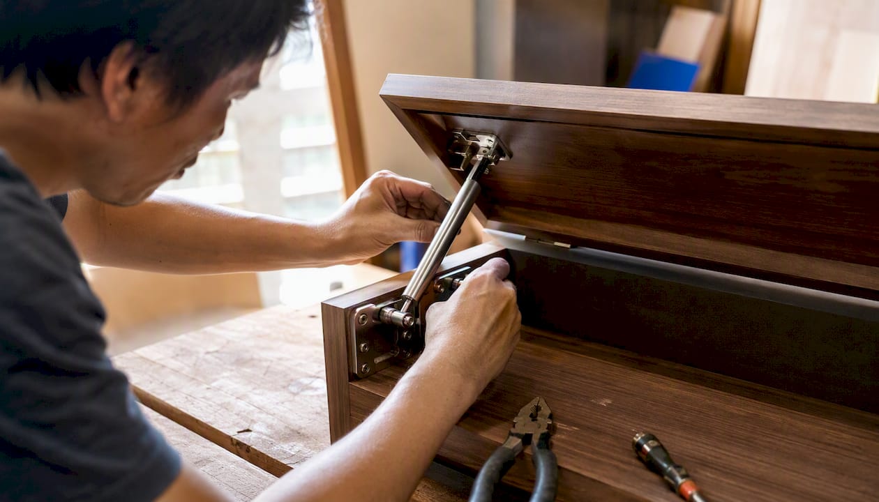 Carpenter hands installing Murphy bed piston mechanism