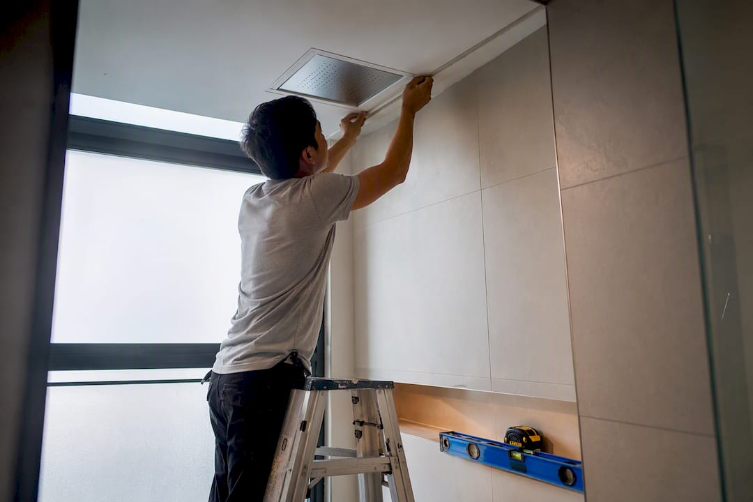 Carpenter fitting trim around shower access panel