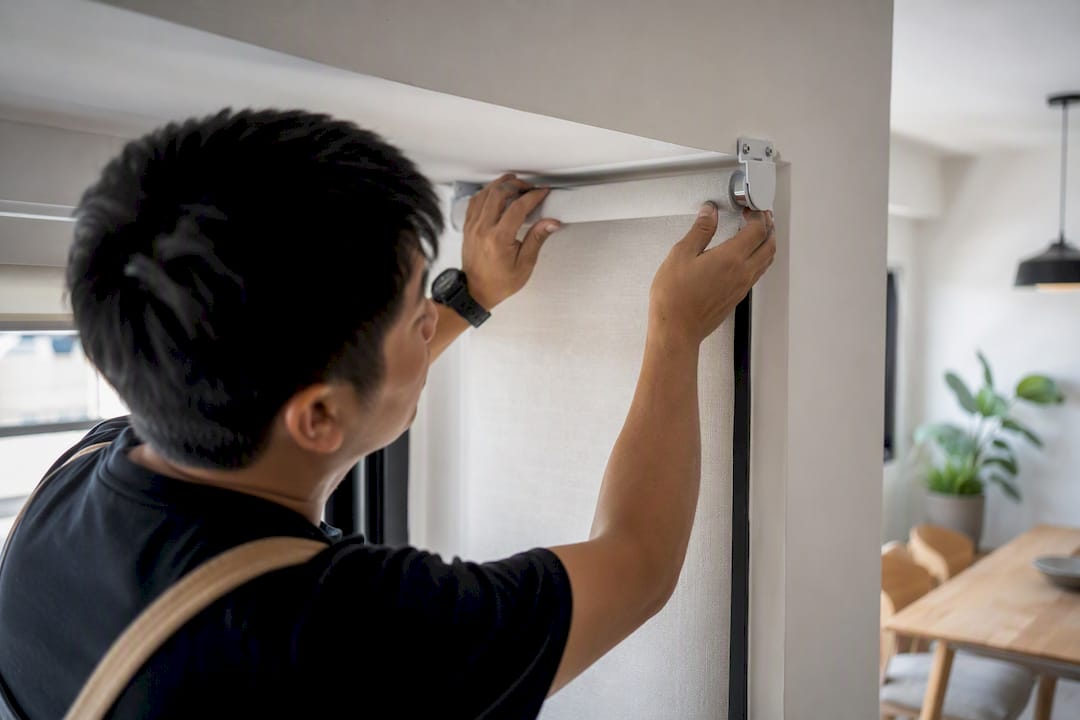 Hands installing roller shade in home