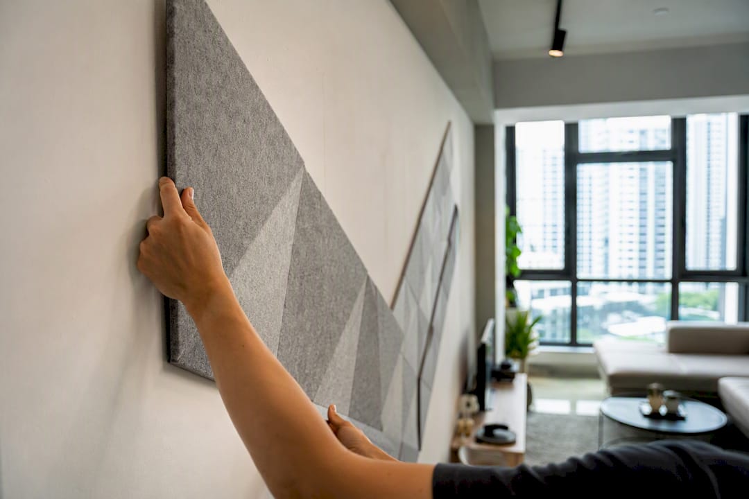 Hands installing acoustic wall panel in Singapore home